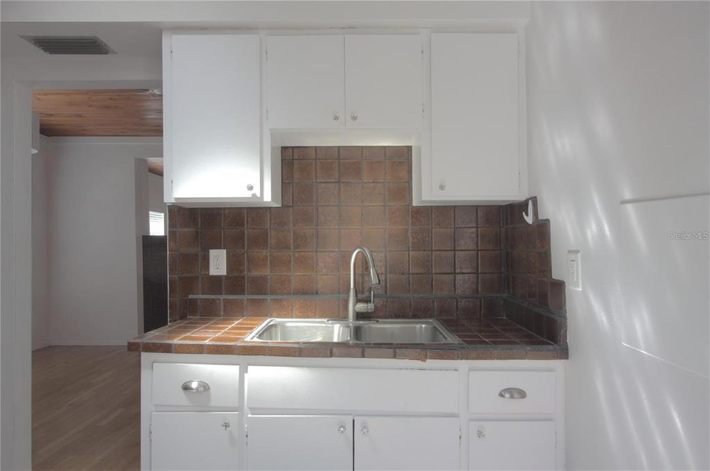 A kitchen sink area features white cabinets, brown tile countertops, and a brown tiled backsplash — 303 S OSPREY AVENUE UNIT 303, SARASOTA, FL