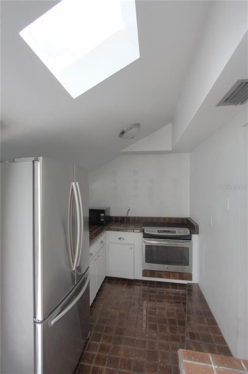 A kitchen with a stainless steel refrigerator, a built-in oven, and brown tile flooring — 303 S OSPREY AVENUE UNIT 303, SARASOTA, FL