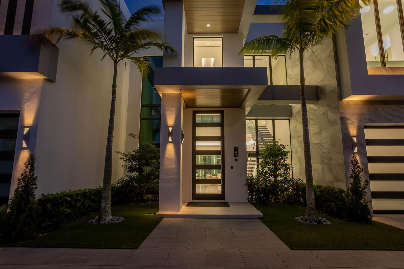 The exterior of a modern two-story home features a glass front door and palm trees — 749 Bamboo Drive, Boca Raton FL 33432, BOCA RATON, FL