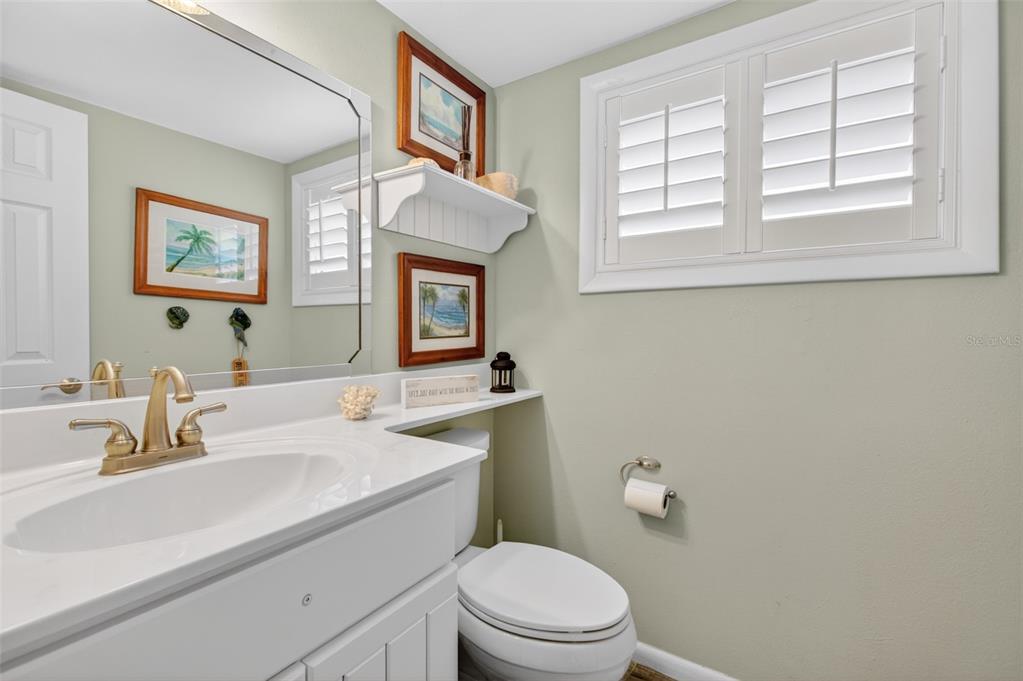 A bathroom features a white vanity, a toilet, a wall-mounted shelf, and plantation shutters — 6300 A1A S UNIT B24U, ST AUGUSTINE, FL