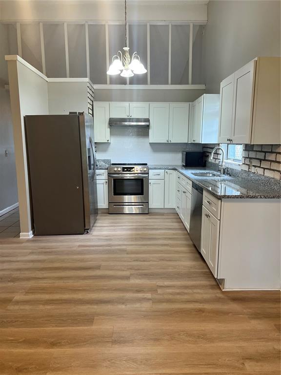 A kitchen with white cabinets, stainless steel appliances, granite countertops, and light wood-look flooring — 267 LAKE THOMAS DRIVE, WINTER HAVEN, FL