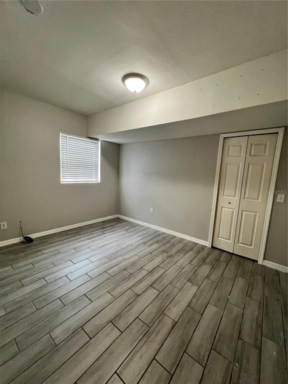 An empty bedroom features gray walls, wood-look tile flooring, a window with blinds, and a closet — 267 LAKE THOMAS DRIVE, WINTER HAVEN, FL