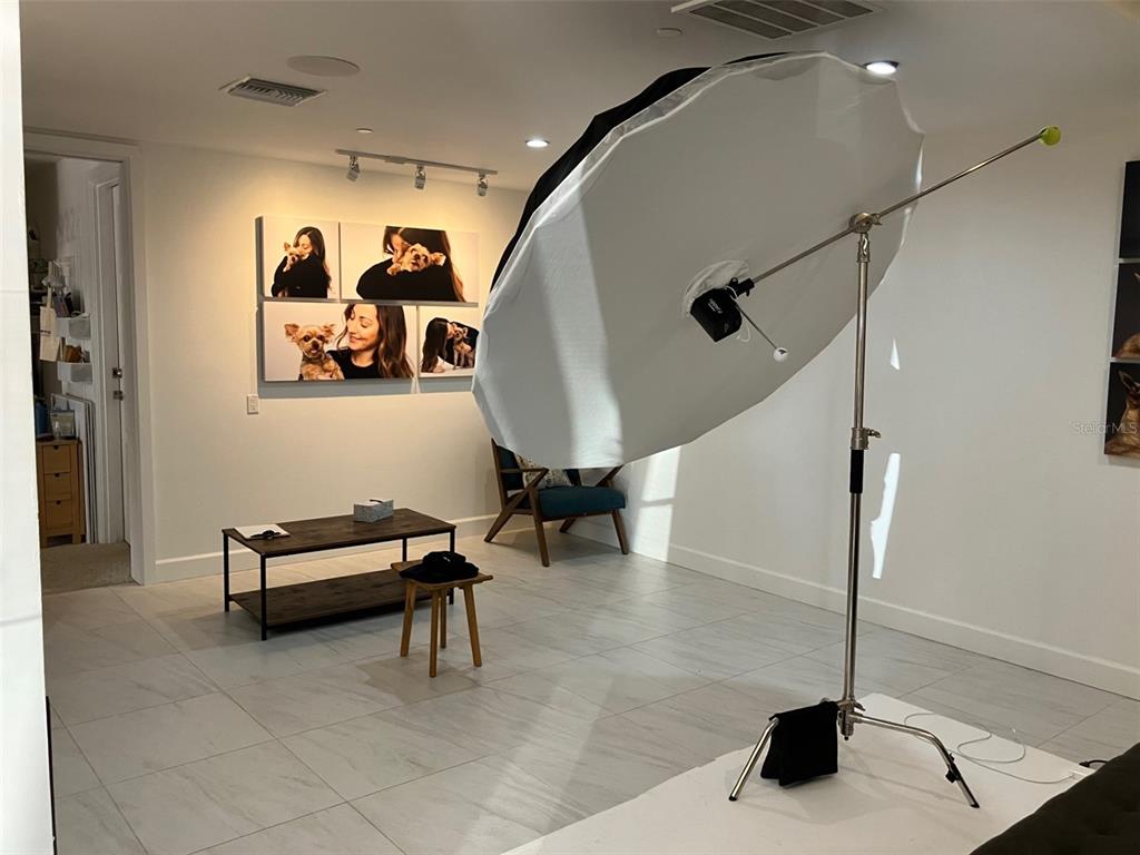 A room with white tile floors, a coffee table, a chair, and photography lighting equipment — 3105 W BAY TO BAY BOULEVARD, TAMPA, FL