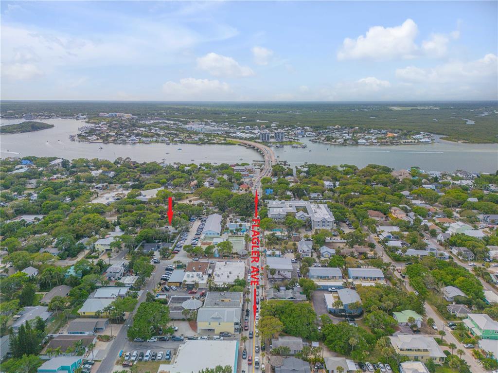 An aerial view shows a coastal town with a bridge, lush vegetation, and Flagler Avenue — 214 COLUMBUS AVENUE, NEW SMYRNA BEACH, FL