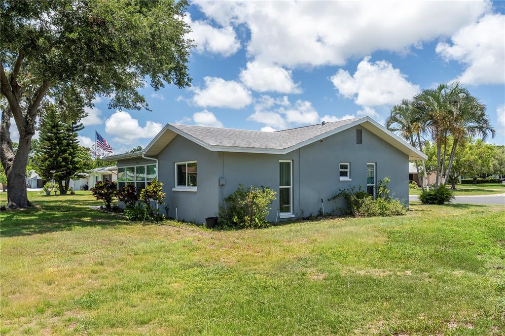 A gray, single-story house with a shingled roof sits on a grassy lot with trees — 4309 HURON LANE, CLEARWATER, FL