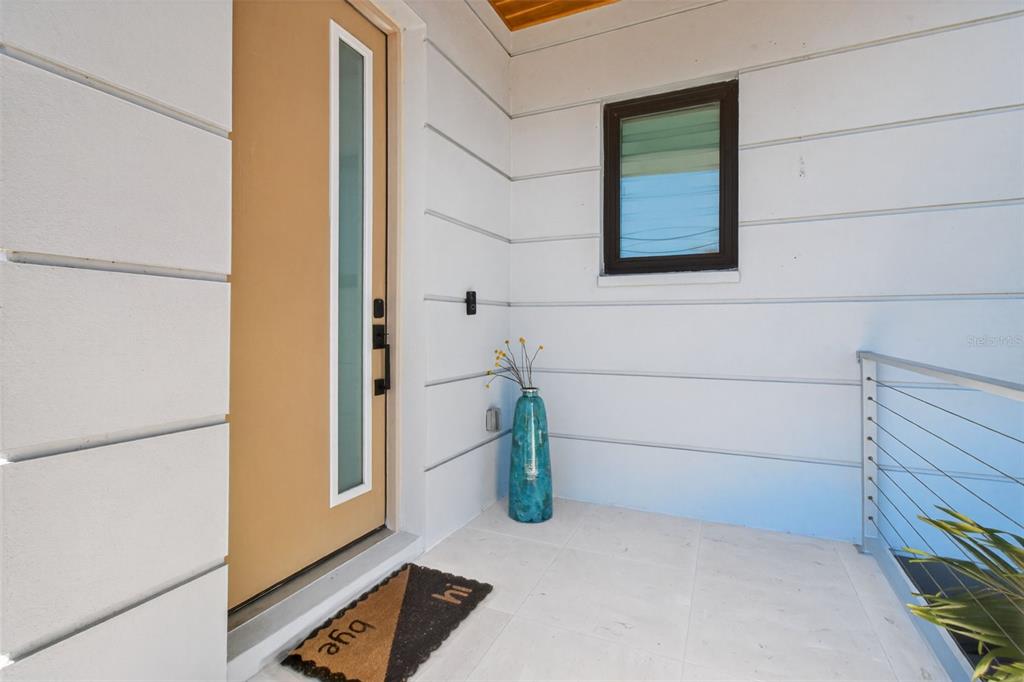A modern front entryway features a tan door, a blue vase, and a doormat — 301 79TH STREET S, ST PETERSBURG, FL