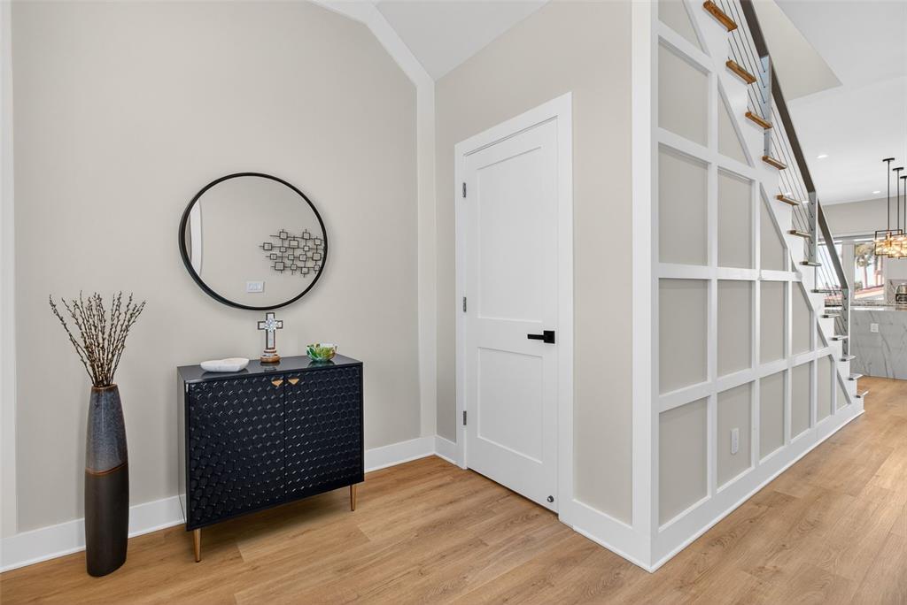 A modern entryway features a black cabinet, a round mirror, and a white paneled staircase — 301 79TH STREET S, ST PETERSBURG, FL