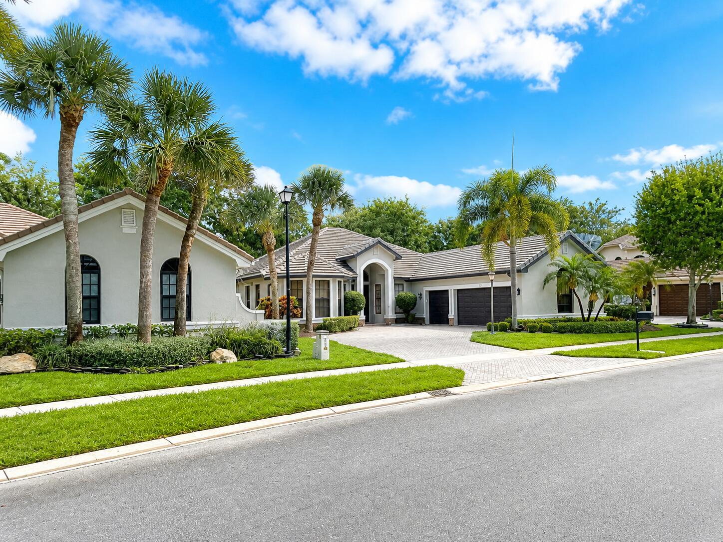 A single-story house with a paved driveway, palm trees, and a manicured lawn — 10295 Trianon Place, Wellington FL 33449, WELLINGTON, FL