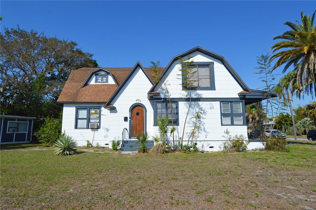 A white house with a gambrel roof and a brown arched front door — 2800 DARTMOUTH AVENUE N, ST PETERSBURG, FL