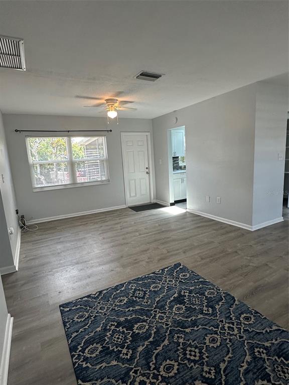 A living room features light gray walls, wood-look flooring, a ceiling fan, and a white door — 155 DOW ROAD, PORT CHARLOTTE, FL