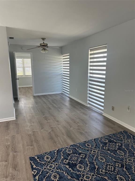 A room with light gray walls, wood-look flooring, a ceiling fan, and two windows with blinds — 155 DOW ROAD, PORT CHARLOTTE, FL
