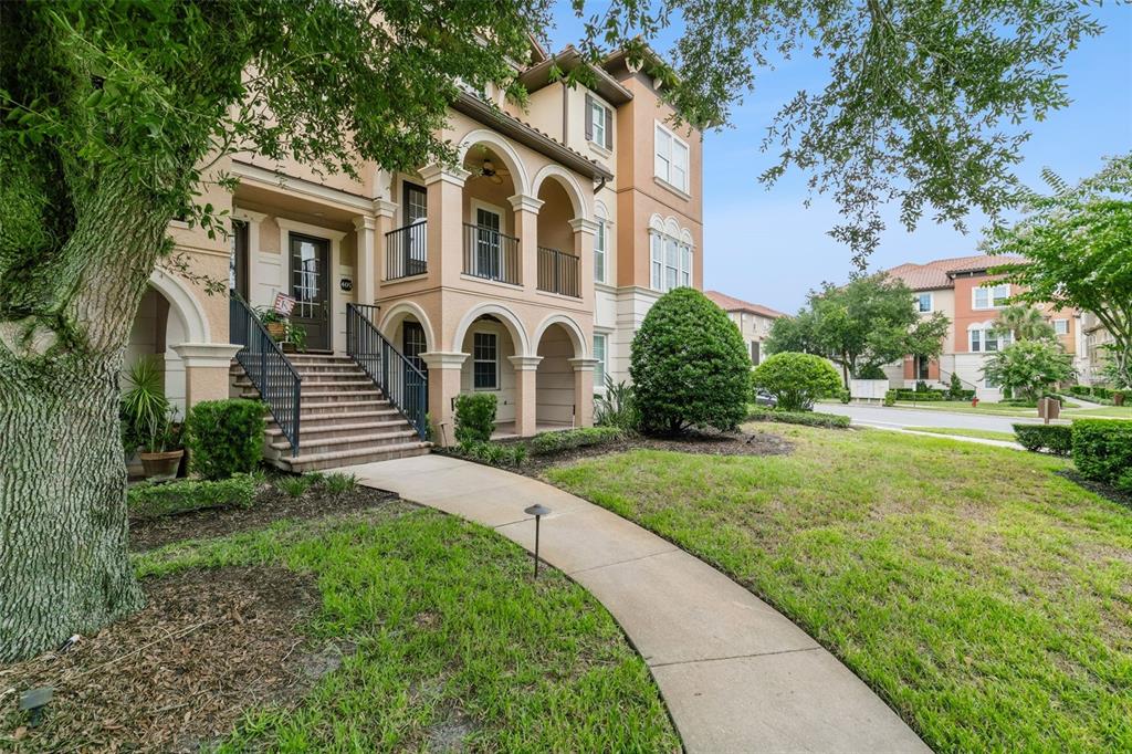 A multi-story tan stucco building with arched balconies and a concrete walkway leading to stairs — 405 PAVIA LOOP, LAKE MARY, FL