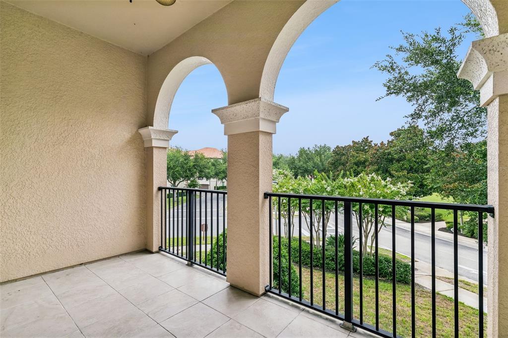 A covered balcony features tiled flooring, arched openings, and black metal railings overlooking a street — 405 PAVIA LOOP, LAKE MARY, FL