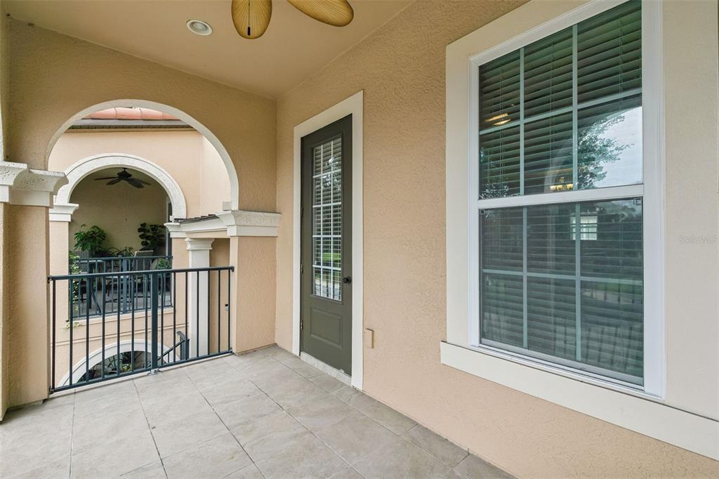 A covered balcony features tiled flooring, a dark green door, and a large window — 405 PAVIA LOOP, LAKE MARY, FL