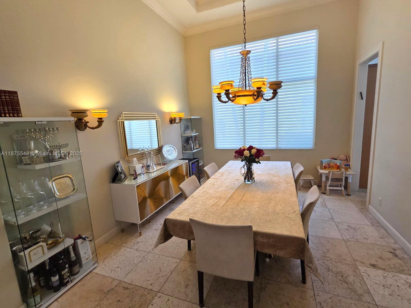 A dining room features a long table, chandelier, glass display cabinet, and large window — 7030 Islegrove Pl, Boca Raton FL 33433, BOCA RATON, FL