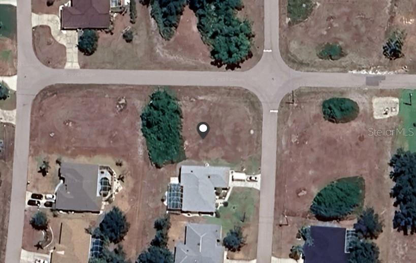 This aerial view shows a vacant residential lot situated between two existing houses on a street — 2355 PRAGUE LANE, PUNTA GORDA, FL