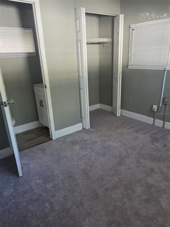 A bedroom with gray carpet, a closet, and an adjacent small bathroom with a vanity — 906 ESTELLE AVENUE, BRANDON, FL