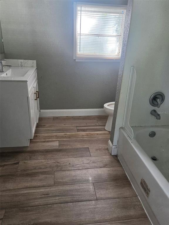 A bathroom features a white vanity, a toilet, a bathtub, and wood-look tile flooring — 906 ESTELLE AVENUE, BRANDON, FL