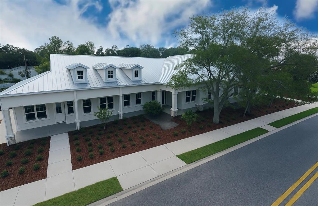 An exterior view of a white building with a metal roof and three dormer windows — 981 VINELAND ROAD, WINTER GARDEN, FL