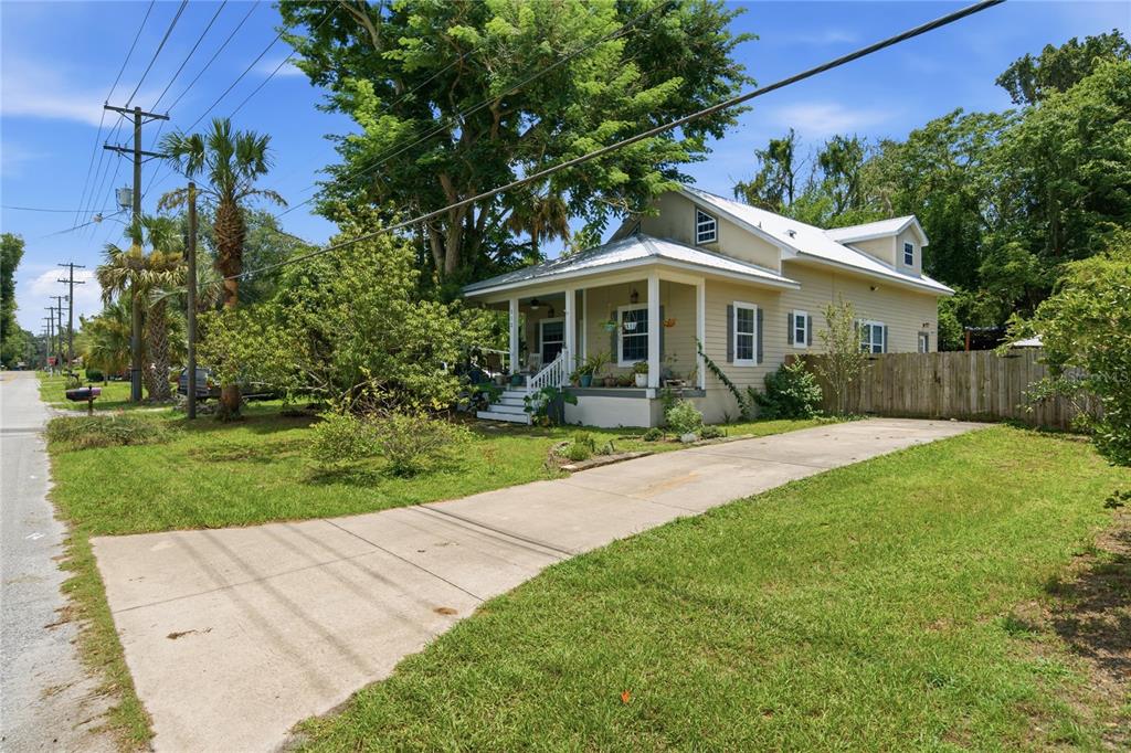 A light yellow, two-story house with a front porch and a concrete driveway — 512 SE 9TH STREET, OCALA, FL