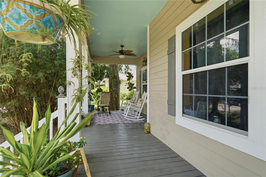 A covered front porch features a light blue ceiling, wooden decking, and white rocking chairs — 512 SE 9TH STREET, OCALA, FL