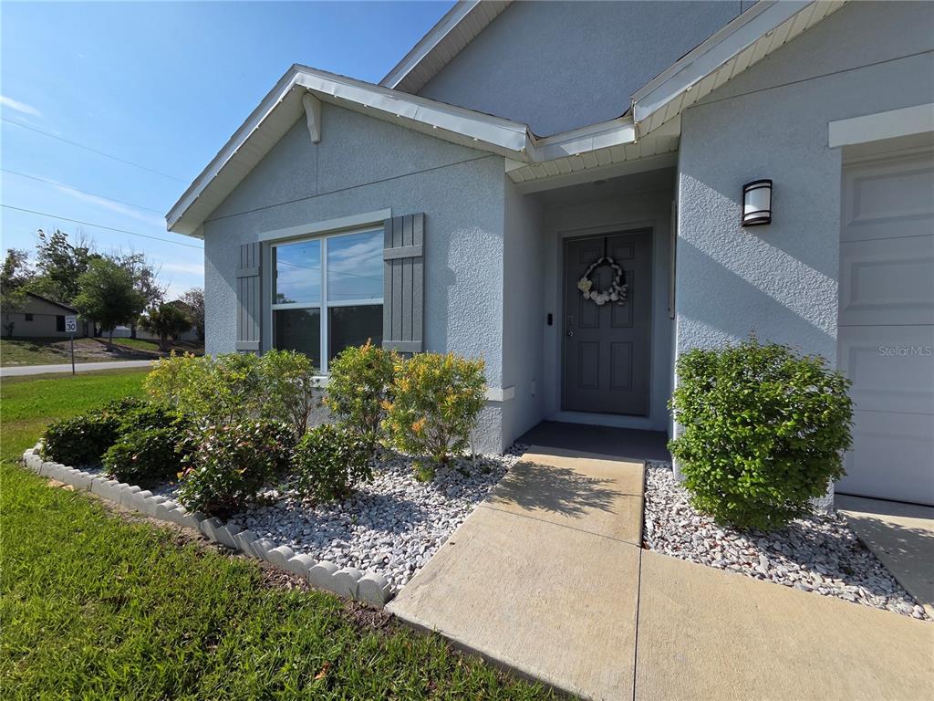 The exterior of a light blue house features a front door, window, and landscaping — 4446 BAYRIDGE COURT, SPRING HILL, FL