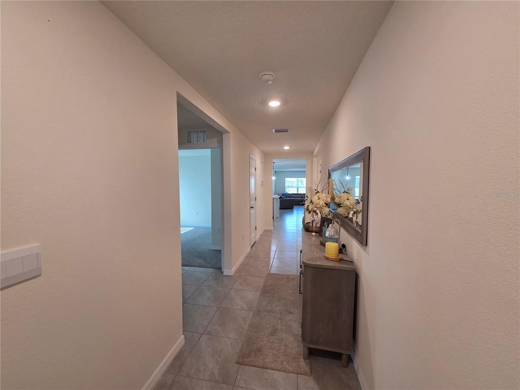 A tiled hallway leads to an open living area with a console table and mirror — 4446 BAYRIDGE COURT, SPRING HILL, FL
