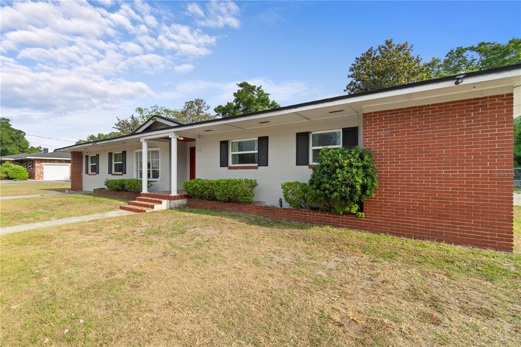 A single-story house features a red brick facade, light gray siding, and a covered entryway — 1910 NW 14TH STREET, OCALA, FL