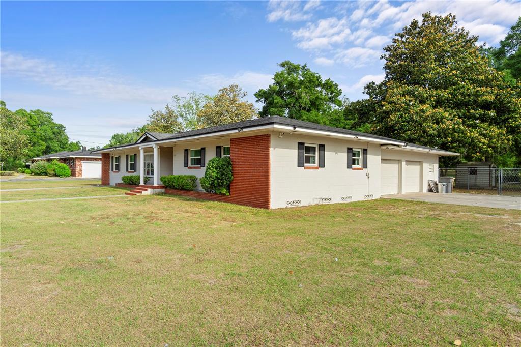 A single-story ranch-style house with a brick and white exterior, attached garage, and lawn — 1910 NW 14TH STREET, OCALA, FL