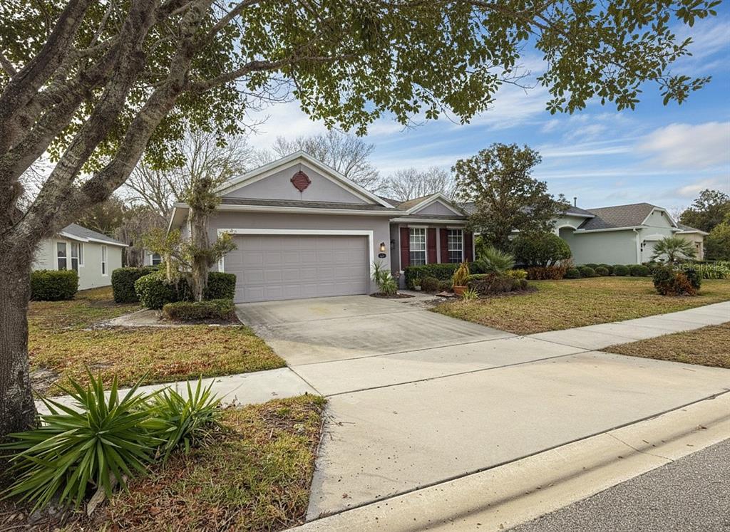 A single-story suburban house with a gray garage, beige siding, and a concrete driveway — 109 AVENHAM DRIVE, DELAND, FL