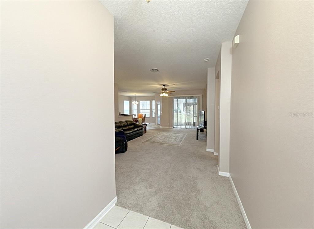 A view from a tiled entryway looking into a carpeted living room with sliding doors — 109 AVENHAM DRIVE, DELAND, FL
