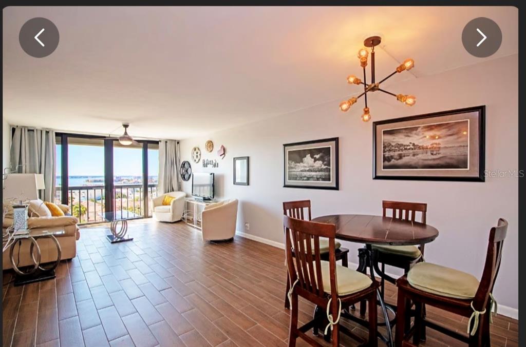 An open-concept living and dining area features wood-look tile flooring and a balcony with water views — 255 DOLPHIN POINT UNIT 2, CLEARWATER BEACH, FL