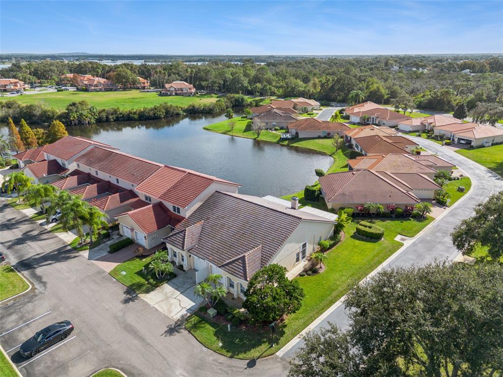 An aerial view shows a residential complex with tile roofs surrounding a central pond — 2202 GARDEN LAKE DRIVE, WINTER HAVEN, FL