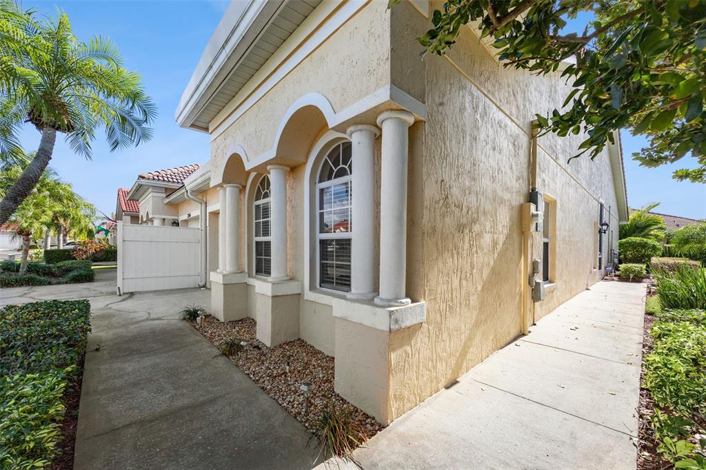 The exterior of a tan stucco house features arched windows, decorative columns, and a walkway — 2202 GARDEN LAKE DRIVE, WINTER HAVEN, FL