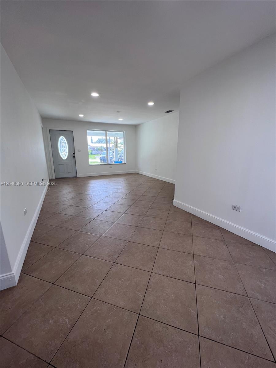 An empty room features white walls, recessed lighting, and brown diagonal-set floor tiles — 600 N 70th Ter, Hollywood FL 33024, HOLLYWOOD, FL