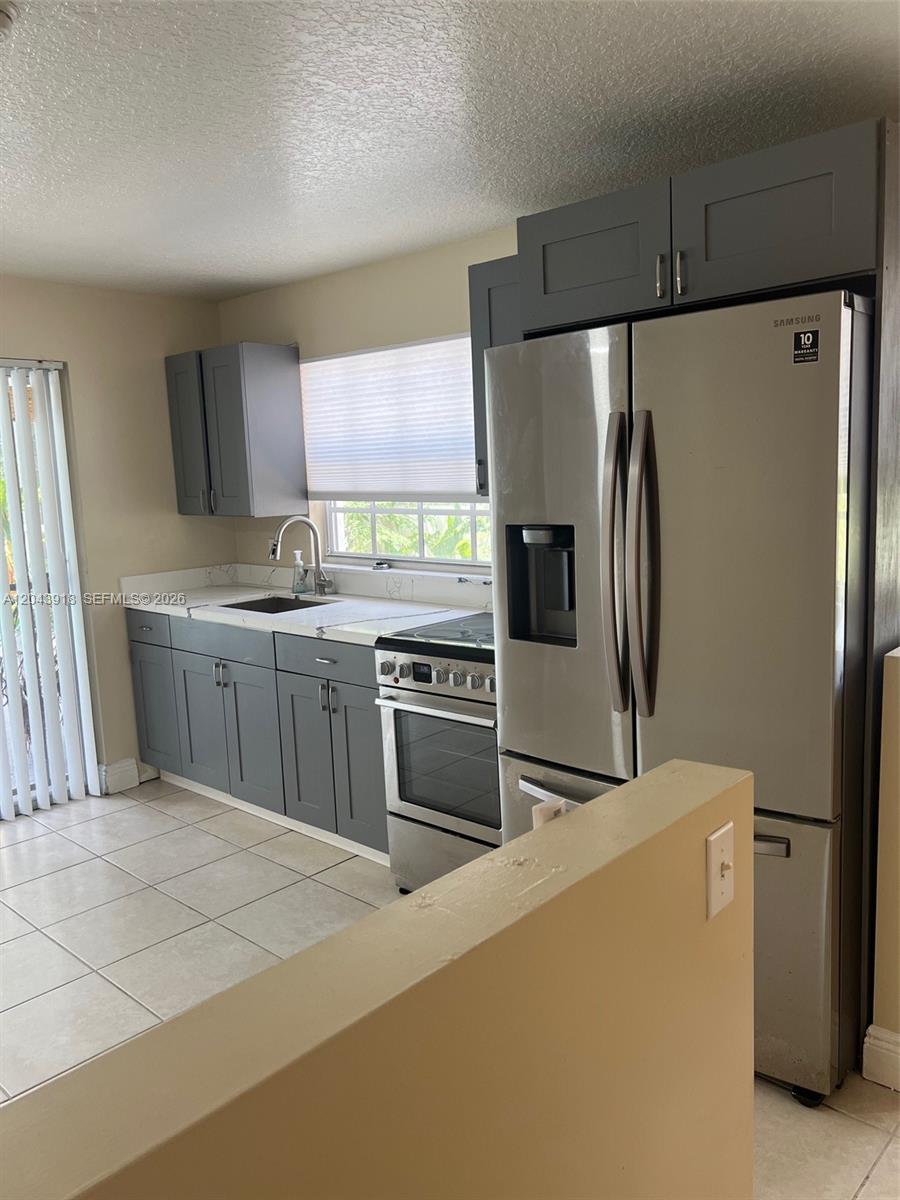 A kitchen features gray cabinets, stainless steel appliances, and light-colored tile flooring — 0 East Dr. # 0, North Miami Beach FL 33162, NORTH MIAMI BEACH, FL