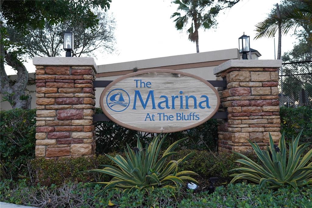 A stone-pillared monument sign displays the name The Marina At The Bluffs — 2101 MARINA ISLE WAY UNIT 104, JUPITER, FL