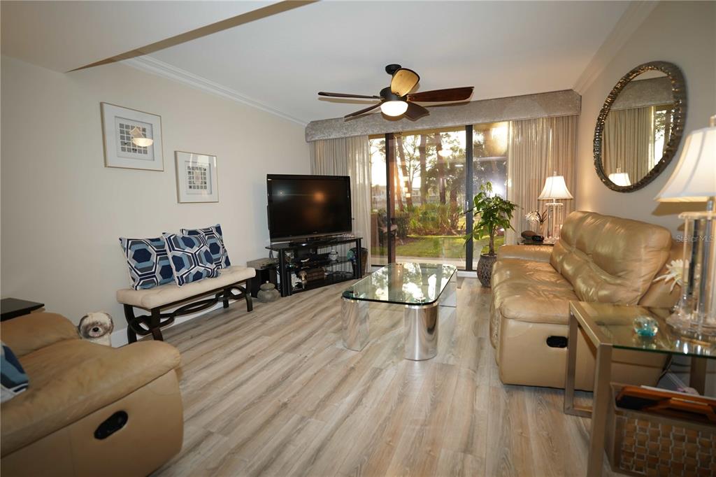 A living room features light wood-look flooring, a tan leather sofa, and a glass coffee table — 2101 MARINA ISLE WAY UNIT 104, JUPITER, FL
