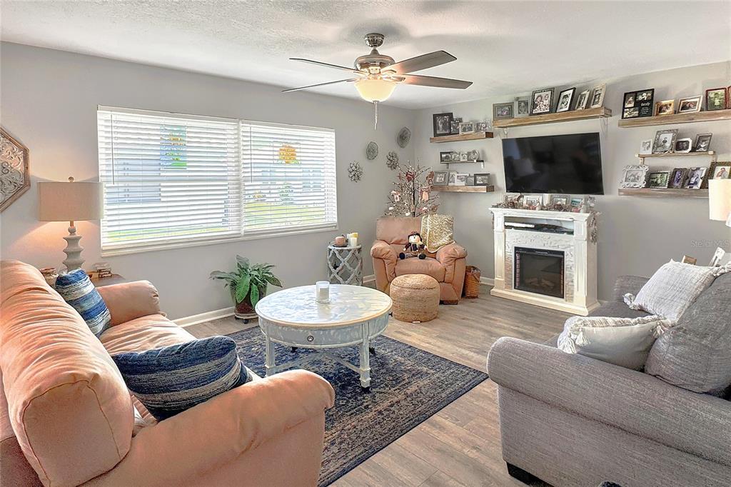 A living room features two sofas, a fireplace, a ceiling fan, and wall-mounted shelving — 3515 AMITY AVENUE UNIT 3515, LAKELAND, FL