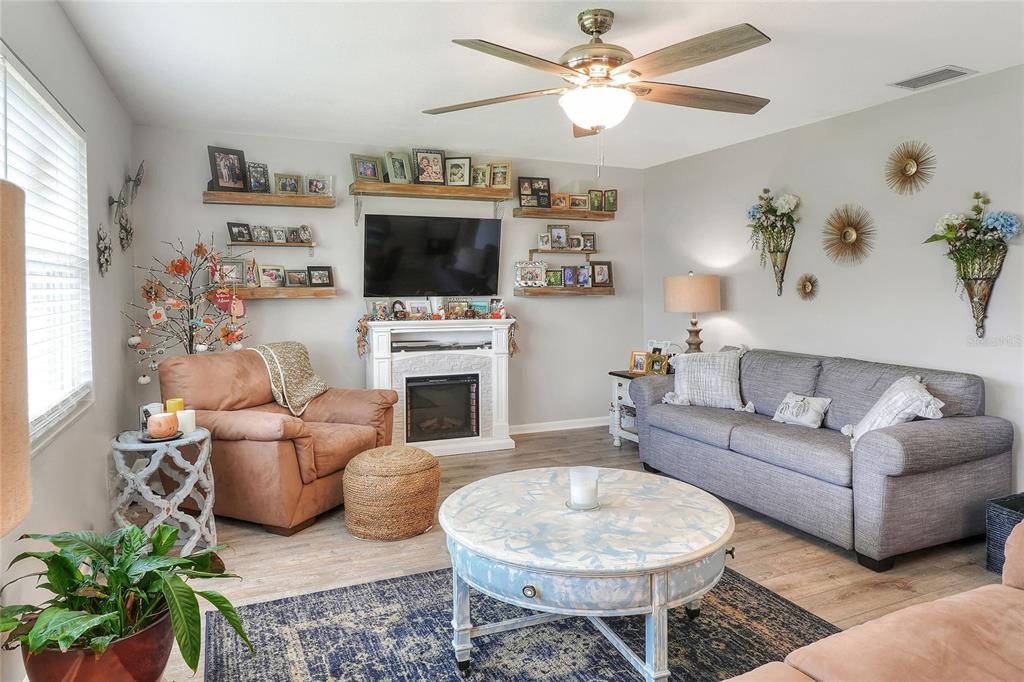 A living room features a fireplace, a television, a grey sofa, and a round table — 3515 AMITY AVENUE UNIT 3515, LAKELAND, FL
