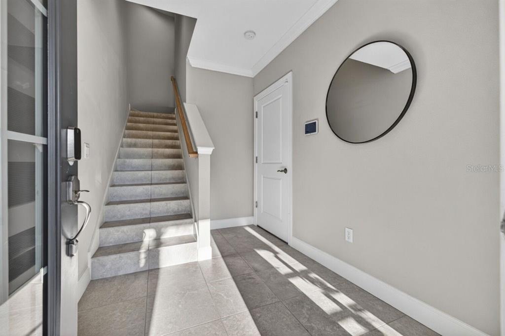 An entryway features a tiled floor, a staircase with a wooden railing, and a round mirror — 4069 ROCKY SHORES DRIVE, TAMPA, FL