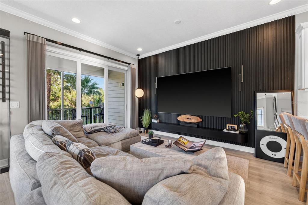 A living room features a large gray sectional, a black slatted accent wall, and sliding doors — 4069 ROCKY SHORES DRIVE, TAMPA, FL