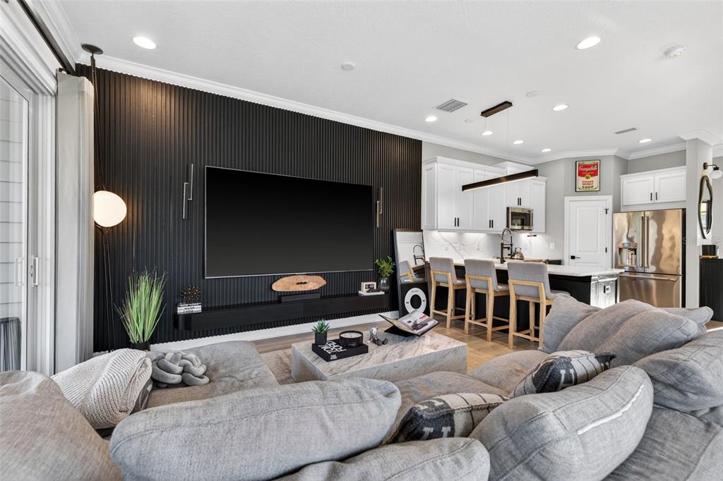 A living room features a black slatted accent wall with a mounted television and kitchen — 4069 ROCKY SHORES DRIVE, TAMPA, FL