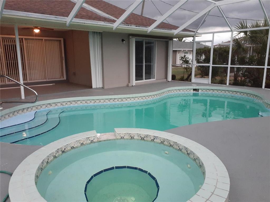 A screened-in patio features a swimming pool, a circular hot tub, and sliding glass doors — 26 CLINTWOOD AVENUE, ENGLEWOOD, FL