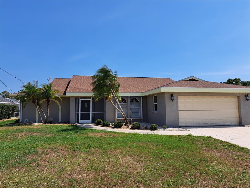 A single-story house with a tan stucco exterior, brown shingled roof, and a two-car garage — 26 CLINTWOOD AVENUE, ENGLEWOOD, FL
