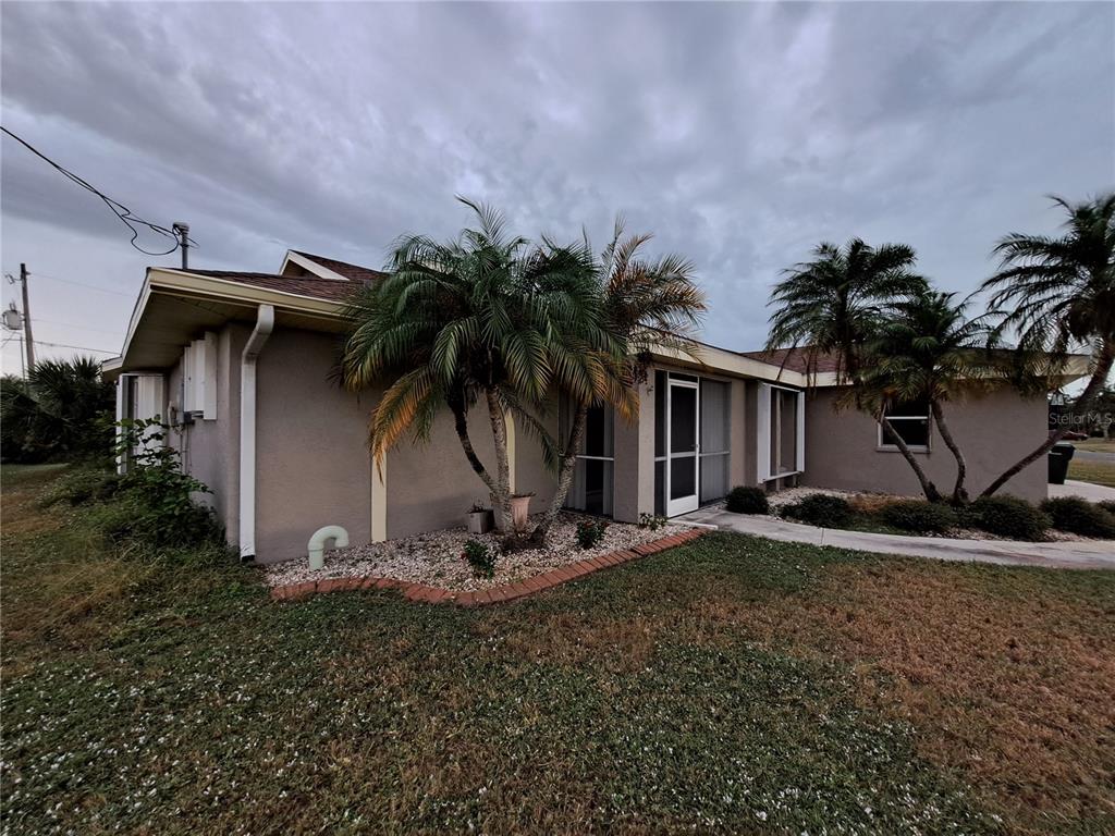 A single-story house with a stucco exterior, palm trees, and a gravel landscaping bed — 26 CLINTWOOD AVENUE, ENGLEWOOD, FL