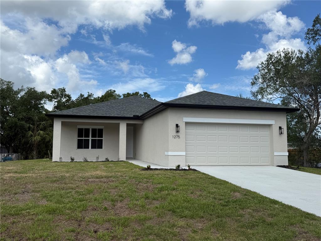 A single-story house with a beige stucco exterior, a two-car garage, and a covered porch — 1275 PERRY STREET, PORT CHARLOTTE, FL