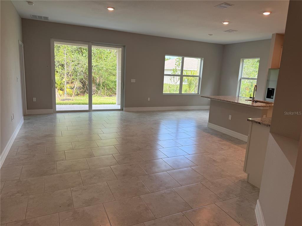 An open-concept living area features tile flooring, a kitchen island, and sliding glass patio doors — 1275 PERRY STREET, PORT CHARLOTTE, FL