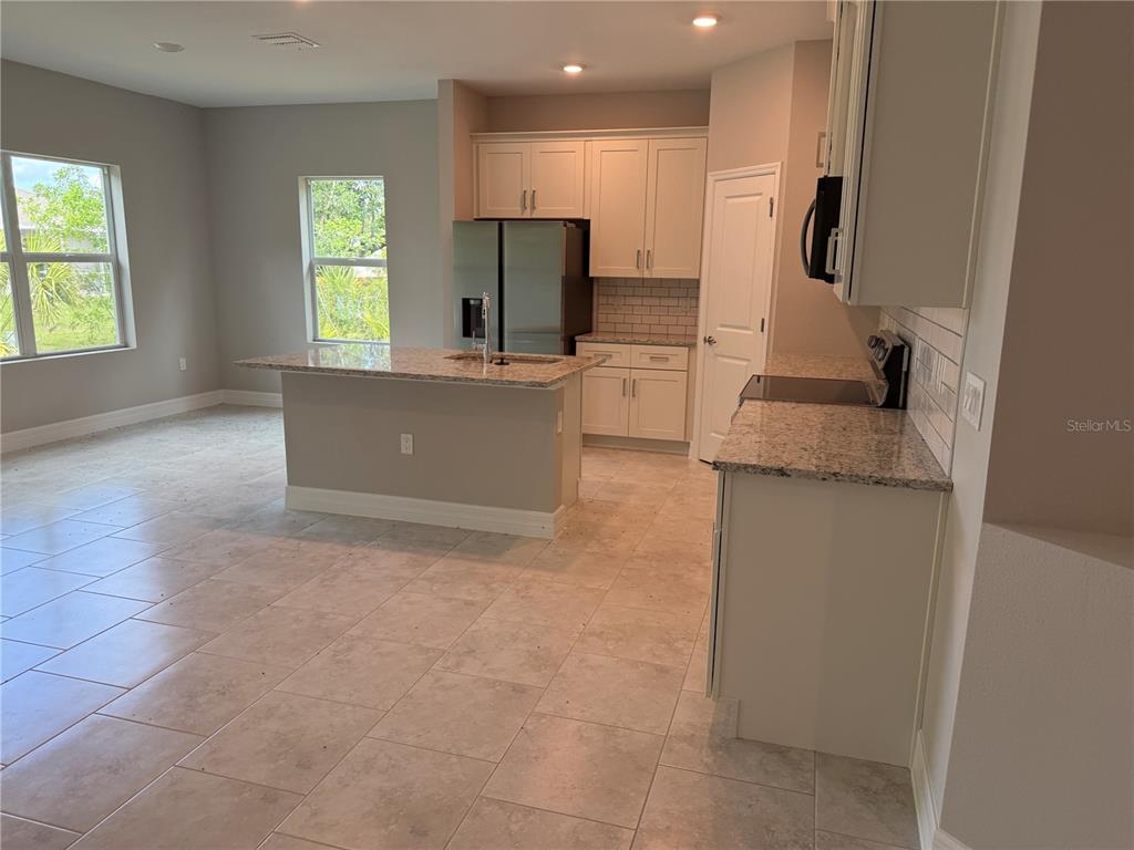 A kitchen features light-colored cabinets, granite countertops, stainless steel appliances, and tile flooring — 1275 PERRY STREET, PORT CHARLOTTE, FL
