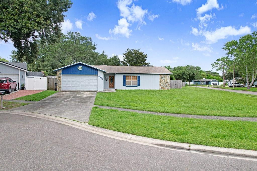 A single-story house with a blue-accented garage, stone siding, and a large front lawn — 4908 CROCKETT COURT, TAMPA, FL
